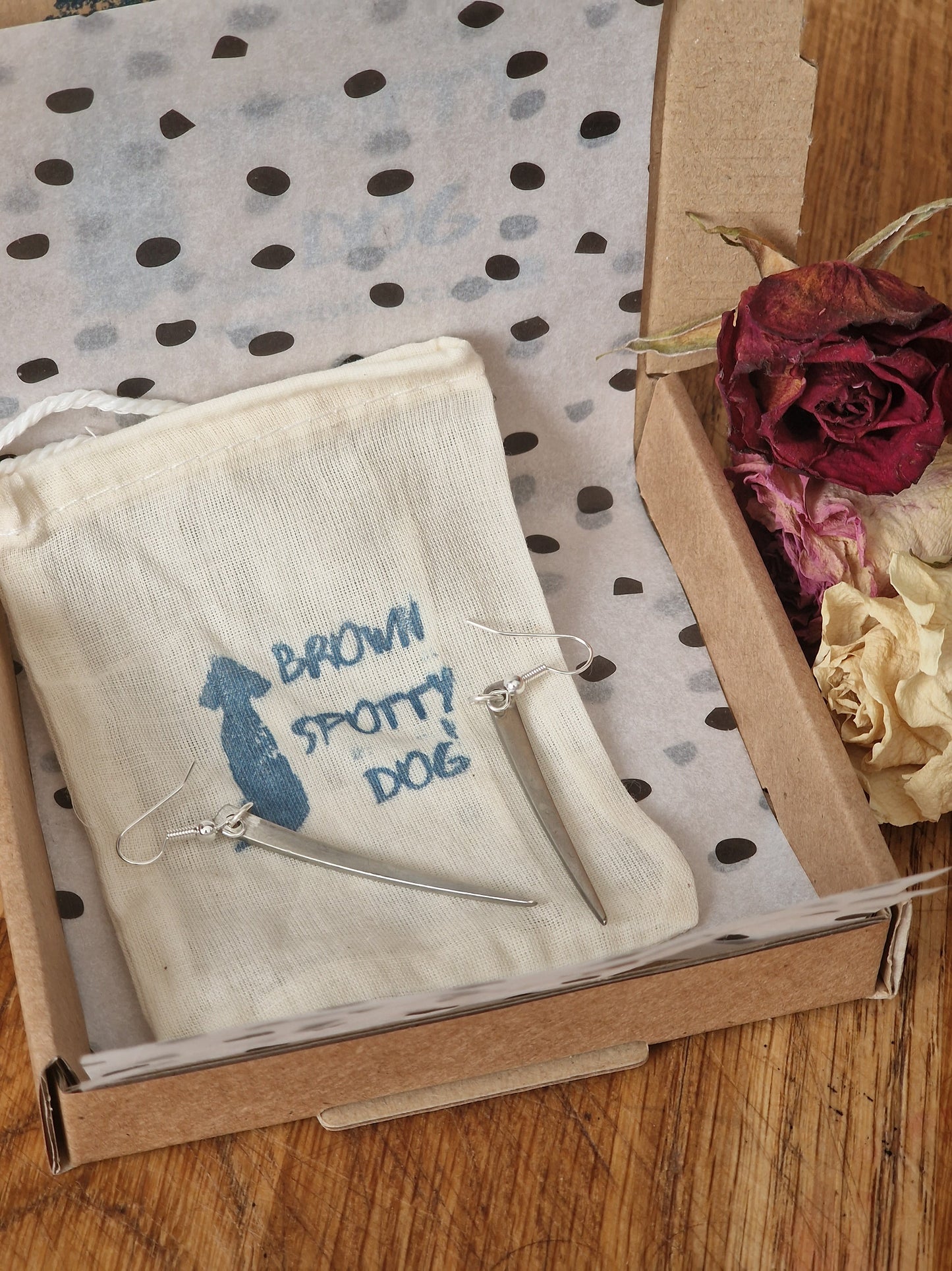 The image shows the packaging for the jewellery. cotton dust bag, with recycled tissue paper and brown kraft postal box